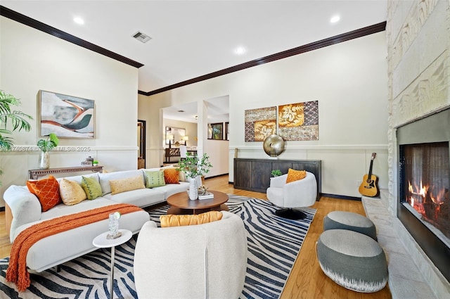 living room featuring ornamental molding, a fireplace, and light hardwood / wood-style flooring