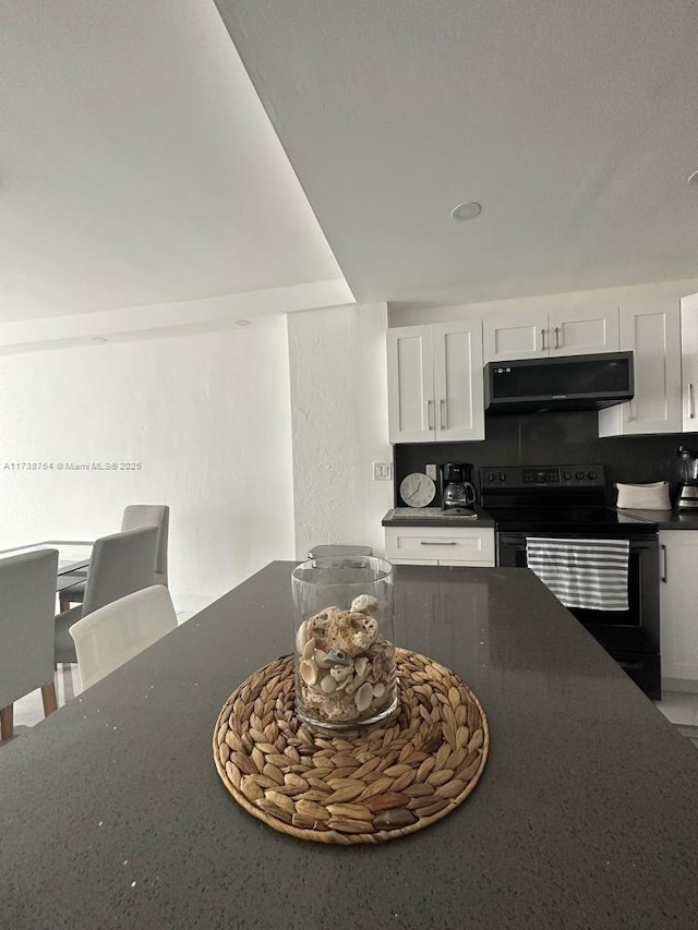 kitchen featuring white cabinets and black range with electric cooktop