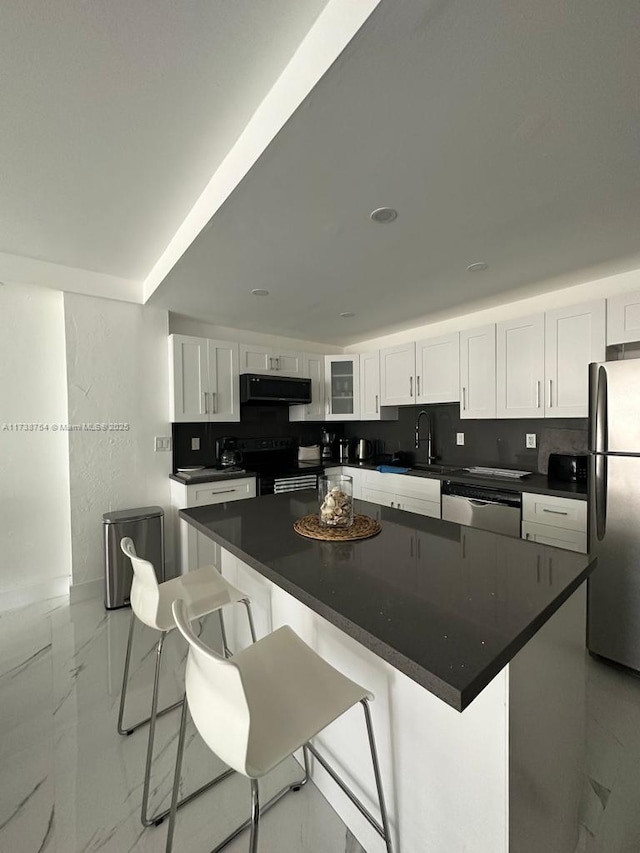 kitchen featuring white cabinetry, backsplash, a kitchen bar, a center island, and stainless steel appliances