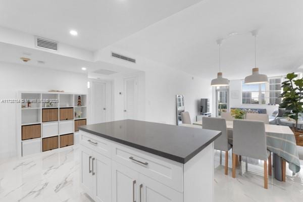 kitchen featuring a center island, pendant lighting, and white cabinets