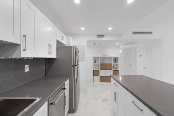 kitchen with sink, decorative backsplash, stainless steel dishwasher, and white cabinets