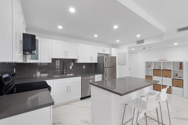 kitchen featuring white cabinetry, appliances with stainless steel finishes, a center island, and sink