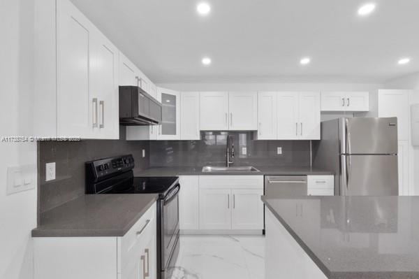 kitchen with white cabinetry, sink, decorative backsplash, stainless steel appliances, and wall chimney exhaust hood