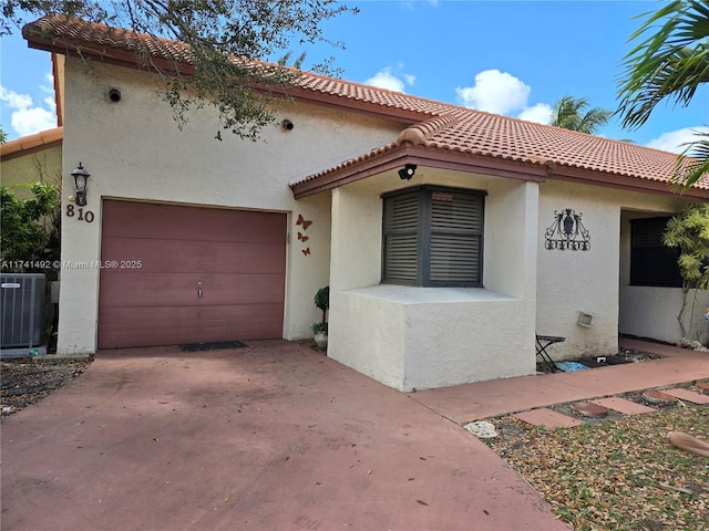 mediterranean / spanish-style home with concrete driveway, cooling unit, a tiled roof, and stucco siding