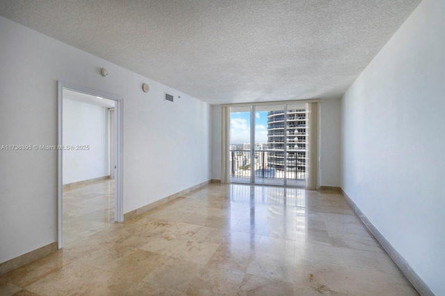 unfurnished room featuring floor to ceiling windows and a textured ceiling