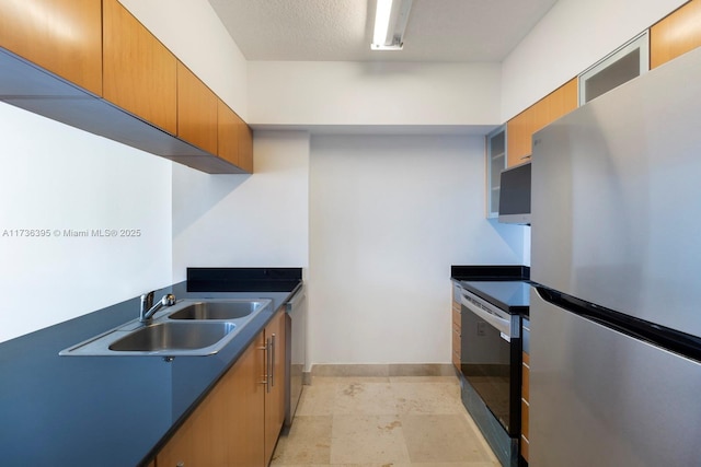 kitchen with sink, a textured ceiling, and stainless steel refrigerator