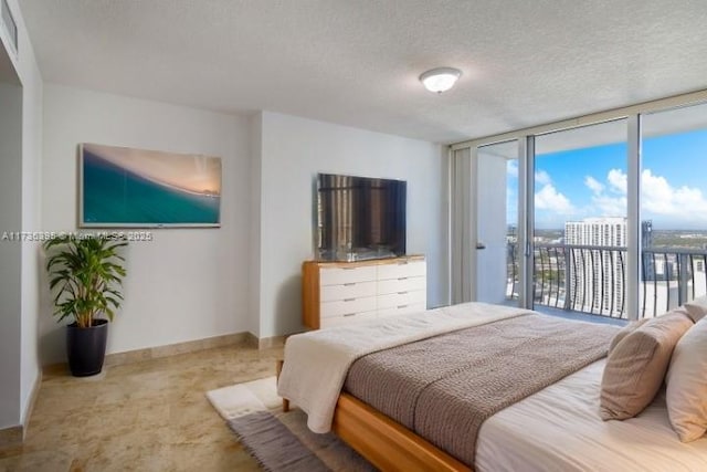 bedroom featuring access to exterior, a wall of windows, and a textured ceiling