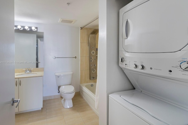 full bathroom with tile patterned flooring, vanity, stacked washer / drying machine,  shower combination, and toilet