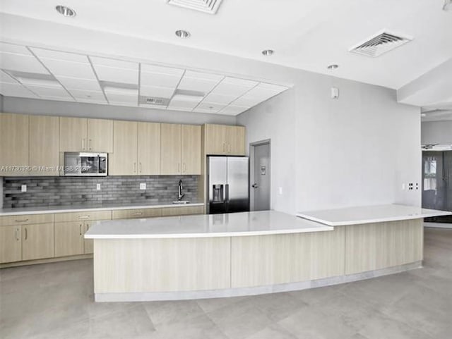 kitchen featuring sink, decorative backsplash, a center island, stainless steel appliances, and light brown cabinets