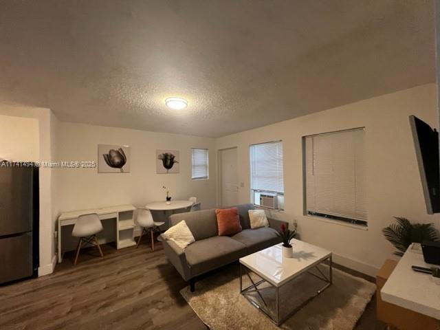 living room with dark hardwood / wood-style flooring, cooling unit, and a textured ceiling