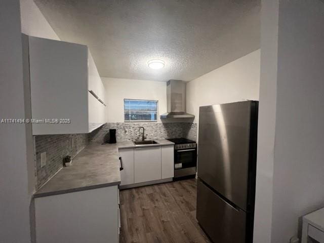 kitchen featuring wall chimney exhaust hood, sink, white cabinetry, tasteful backsplash, and stainless steel appliances