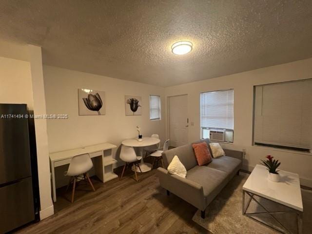 living room featuring wood-type flooring, cooling unit, and a textured ceiling