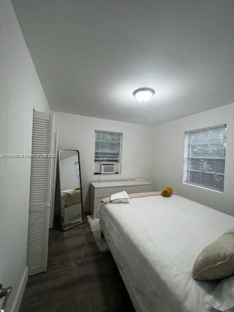 bedroom with cooling unit and dark hardwood / wood-style flooring