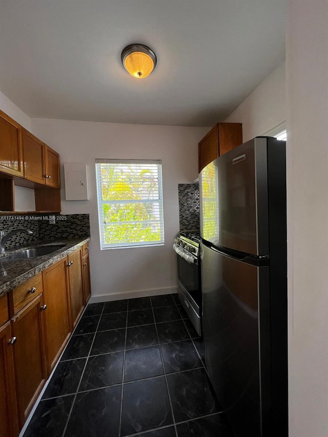 kitchen with stainless steel appliances, sink, decorative backsplash, and dark tile patterned floors