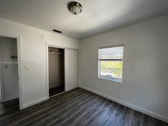 unfurnished bedroom with dark wood-type flooring and a closet