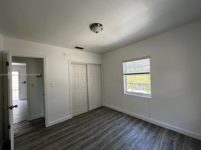 unfurnished bedroom with dark wood-type flooring and a closet