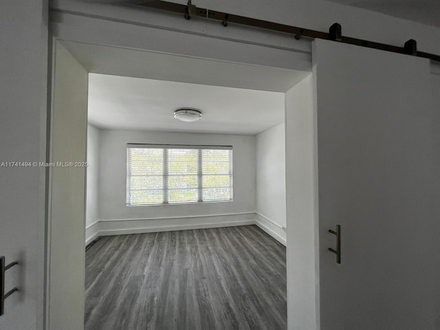 unfurnished room with a barn door and dark hardwood / wood-style floors