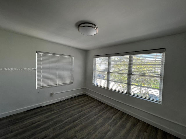 spare room featuring dark wood-type flooring and plenty of natural light