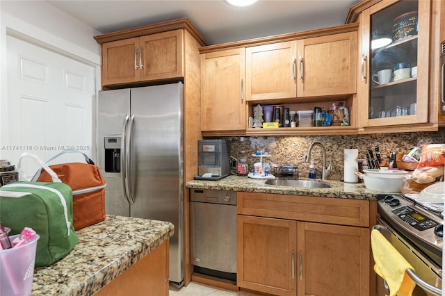 kitchen featuring stainless steel appliances, light stone countertops, sink, and decorative backsplash