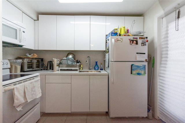 kitchen featuring sink, light tile patterned floors, white cabinets, and white appliances