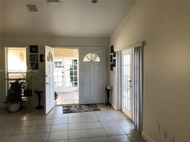 tiled foyer entrance with french doors, a healthy amount of sunlight, and lofted ceiling