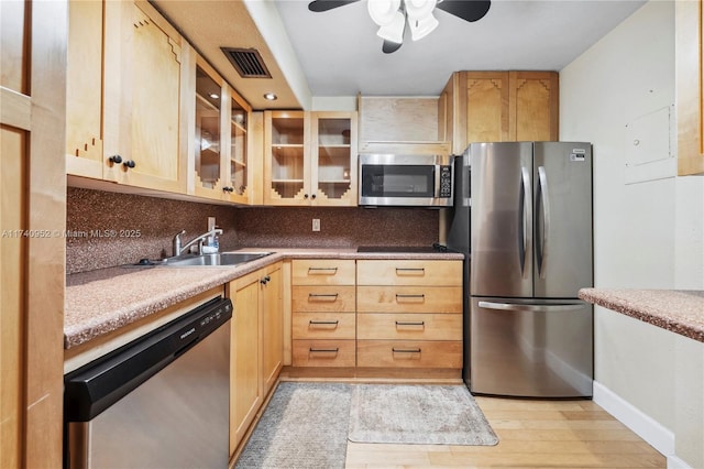 kitchen featuring appliances with stainless steel finishes, light brown cabinetry, and decorative backsplash