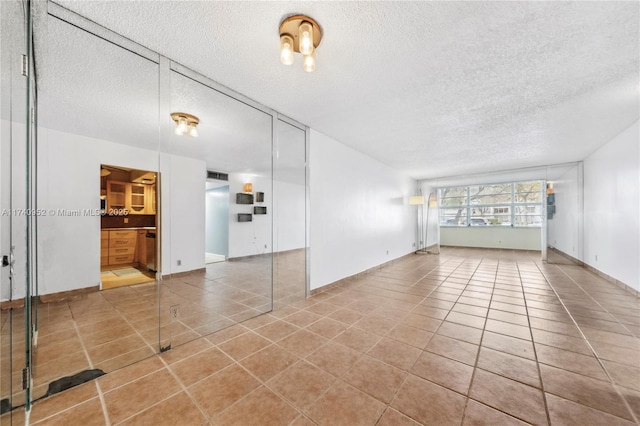 unfurnished living room featuring tile patterned flooring and a textured ceiling