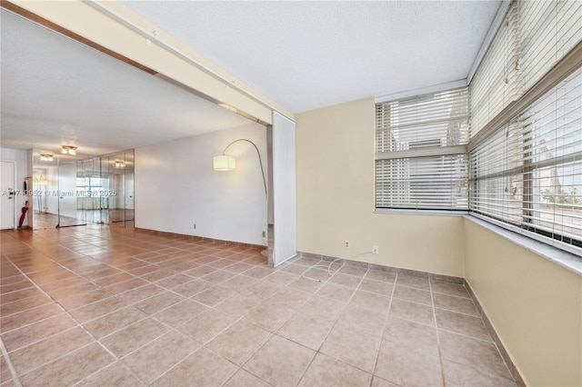 unfurnished room featuring a textured ceiling and light tile patterned flooring