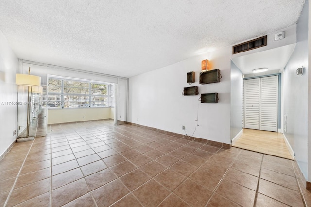 unfurnished living room with tile patterned floors and a textured ceiling