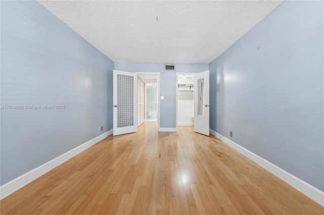 unfurnished room with a textured ceiling and light wood-type flooring