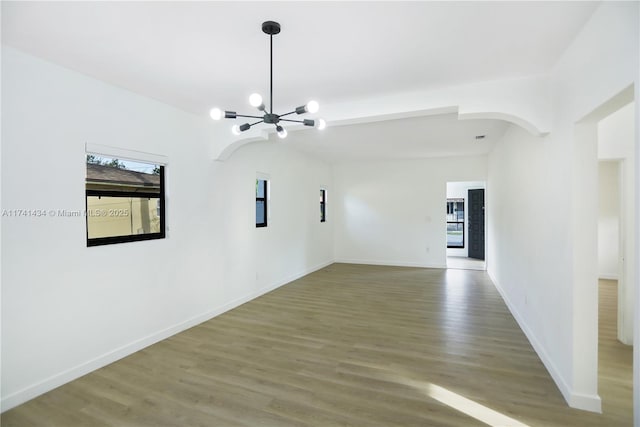 empty room featuring hardwood / wood-style flooring and a notable chandelier