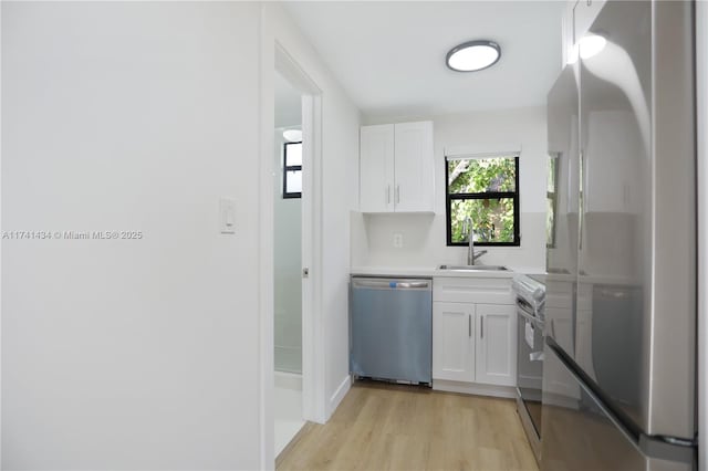 kitchen featuring sink, light hardwood / wood-style floors, white cabinets, and appliances with stainless steel finishes