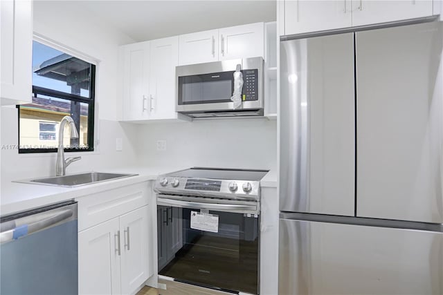 kitchen with stainless steel appliances, sink, and white cabinets