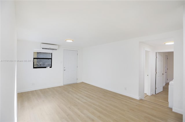 empty room featuring light hardwood / wood-style floors and an AC wall unit