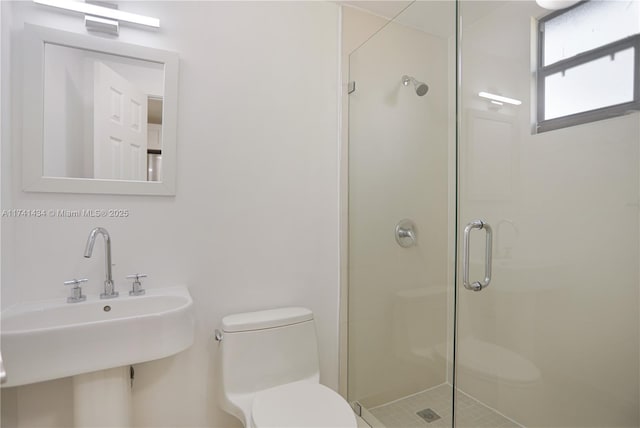 bathroom with sink, a shower with shower door, and toilet