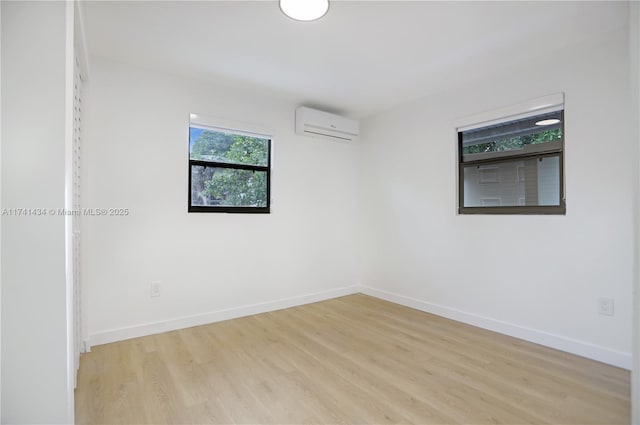 empty room featuring a wall unit AC and light wood-type flooring