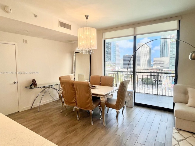 dining area featuring an inviting chandelier, light hardwood / wood-style floors, and floor to ceiling windows