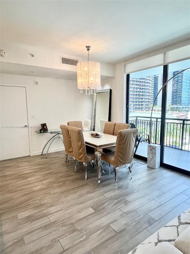 dining area with a notable chandelier, light wood-type flooring, and a wall of windows