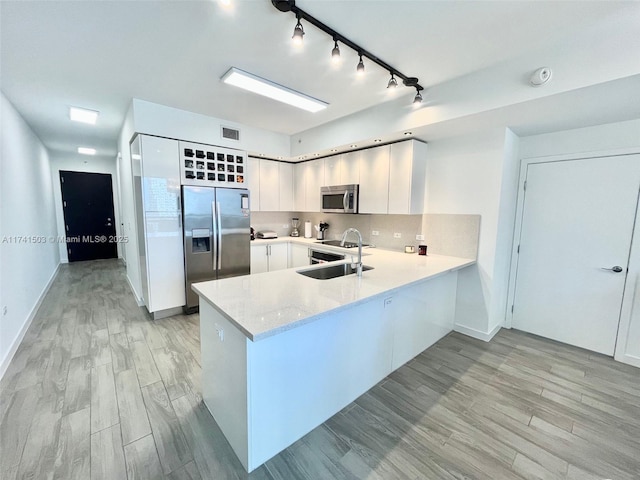 kitchen with stainless steel appliances, light hardwood / wood-style flooring, white cabinets, and decorative backsplash