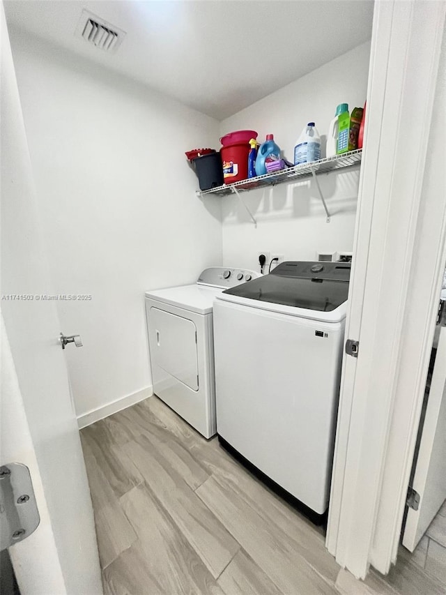 laundry area with washer and clothes dryer and light hardwood / wood-style floors