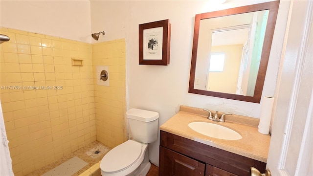 bathroom with vanity, tiled shower, and toilet