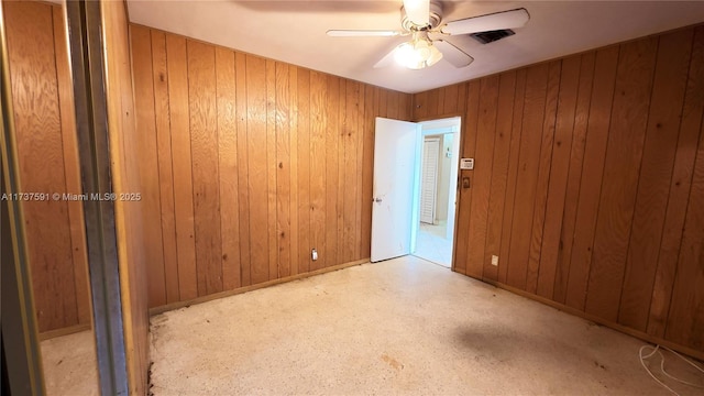 unfurnished room featuring ceiling fan and wood walls