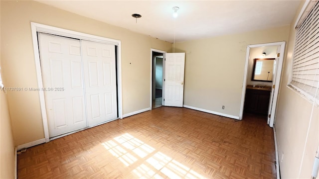 unfurnished bedroom featuring parquet floors, ensuite bath, and a closet