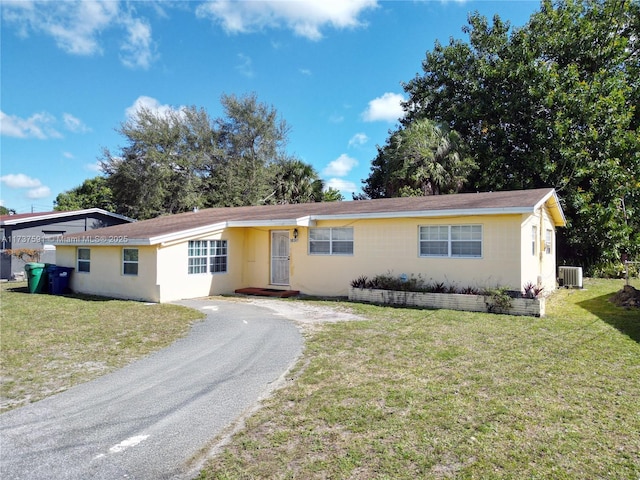 ranch-style house featuring central air condition unit and a front lawn