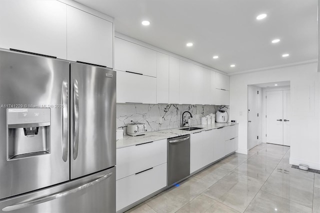 kitchen featuring sink, white cabinetry, light stone counters, appliances with stainless steel finishes, and backsplash