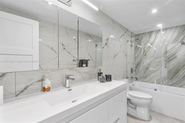 full bathroom featuring vanity, tile walls, shower / bath combination with glass door, and toilet