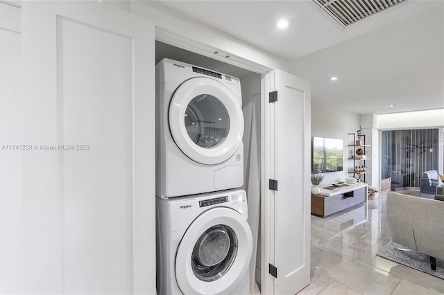 laundry room featuring stacked washer / dryer and light tile patterned floors