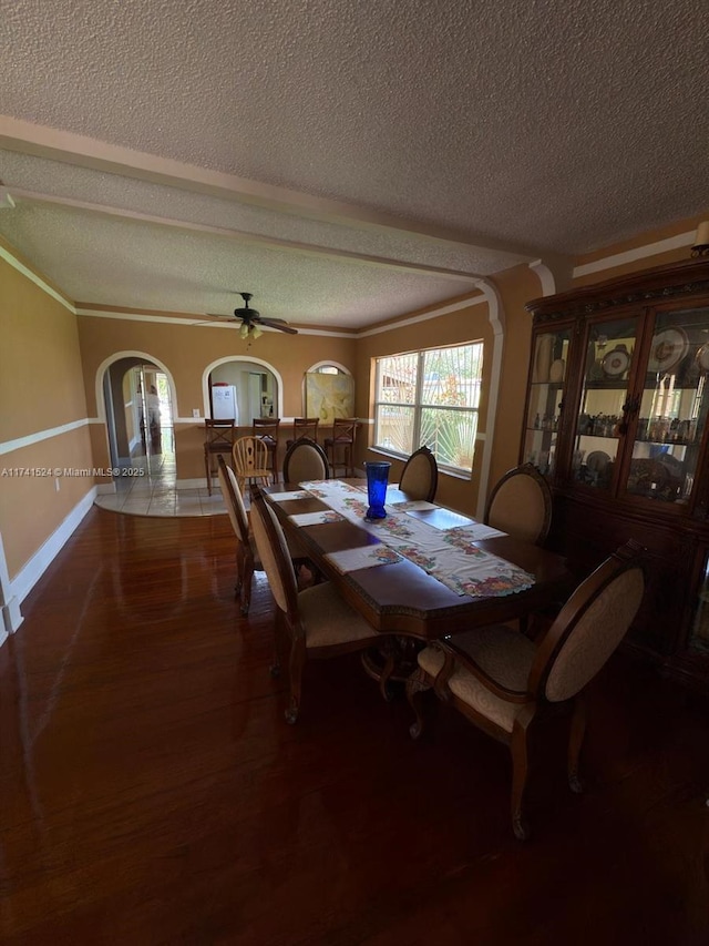 dining area with crown molding, ceiling fan, a textured ceiling, wood finished floors, and baseboards