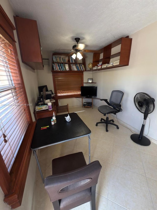 home office featuring a textured ceiling, light tile patterned floors, a ceiling fan, and baseboards