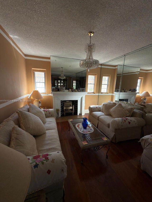 living area featuring a textured ceiling, dark wood-style flooring, a fireplace, and crown molding